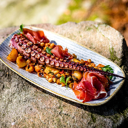 Grilled octopus with thin slices of prosciutto and chickpea stew with potatoes, garlic, and pepper